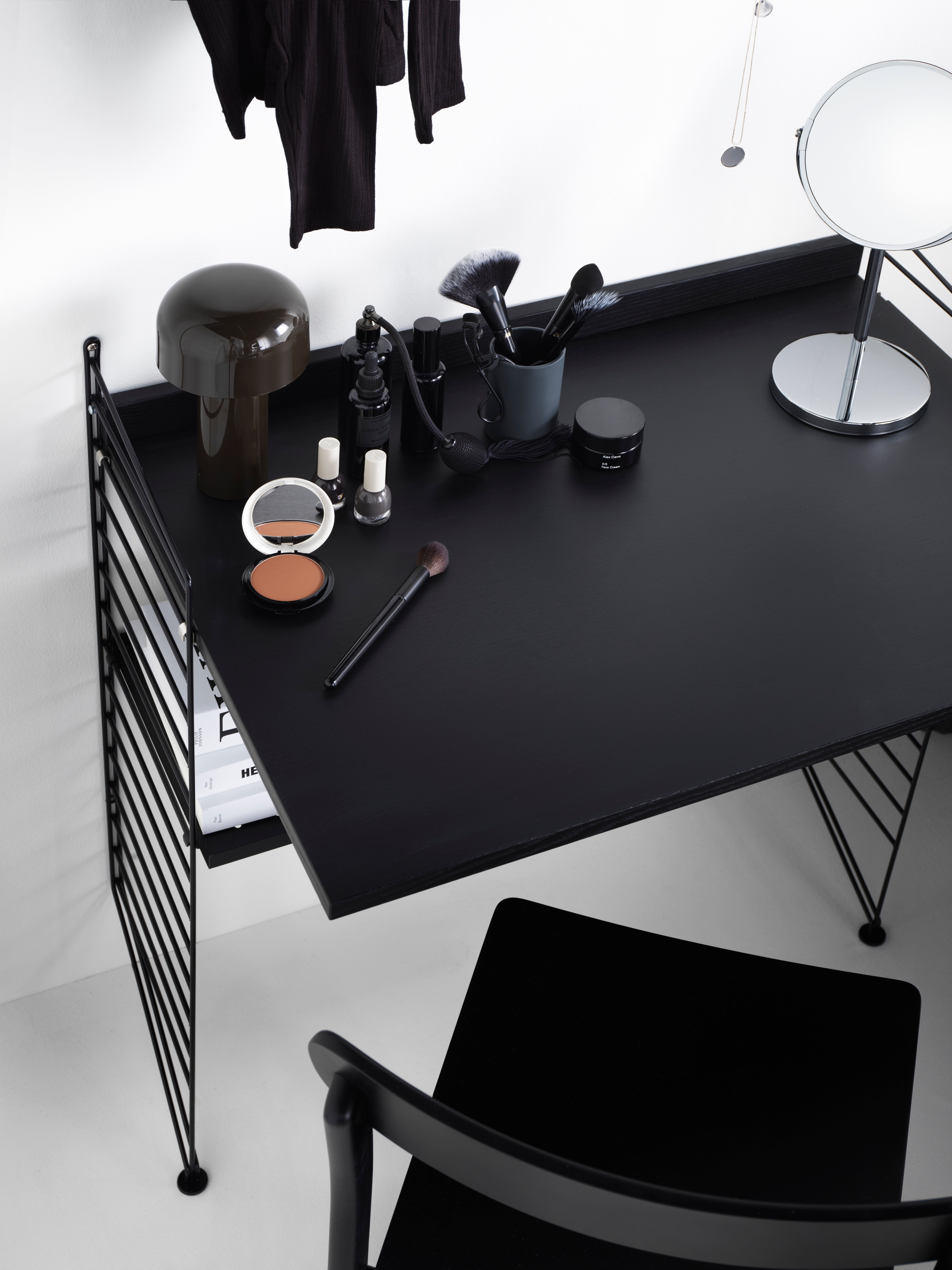 Combinaison d’étagères String conçues pour servir de coiffeuse. Montants de sol noir. Caisson portes coulissantes et bureau en chêne teinté noir avec étagères en métal et accessoires, noir.