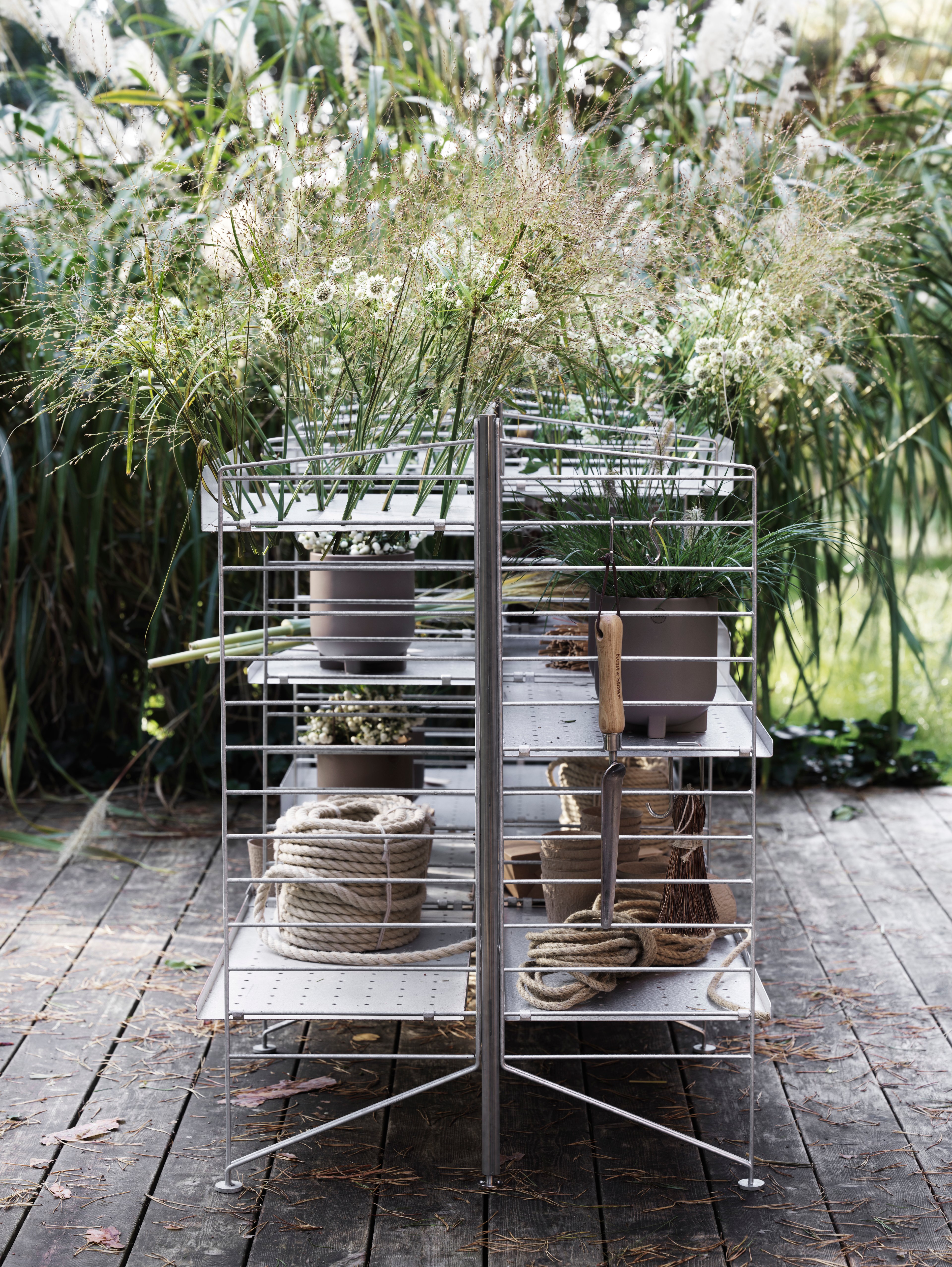 Free-standing galvanized shelf from String System. Galvanized metal shelves with high and low edge along with a galvanized back panel. Vertical hook and double hook in stainless steel to increase storage. Leave your String shelves in galvanized material outdoor all year round.