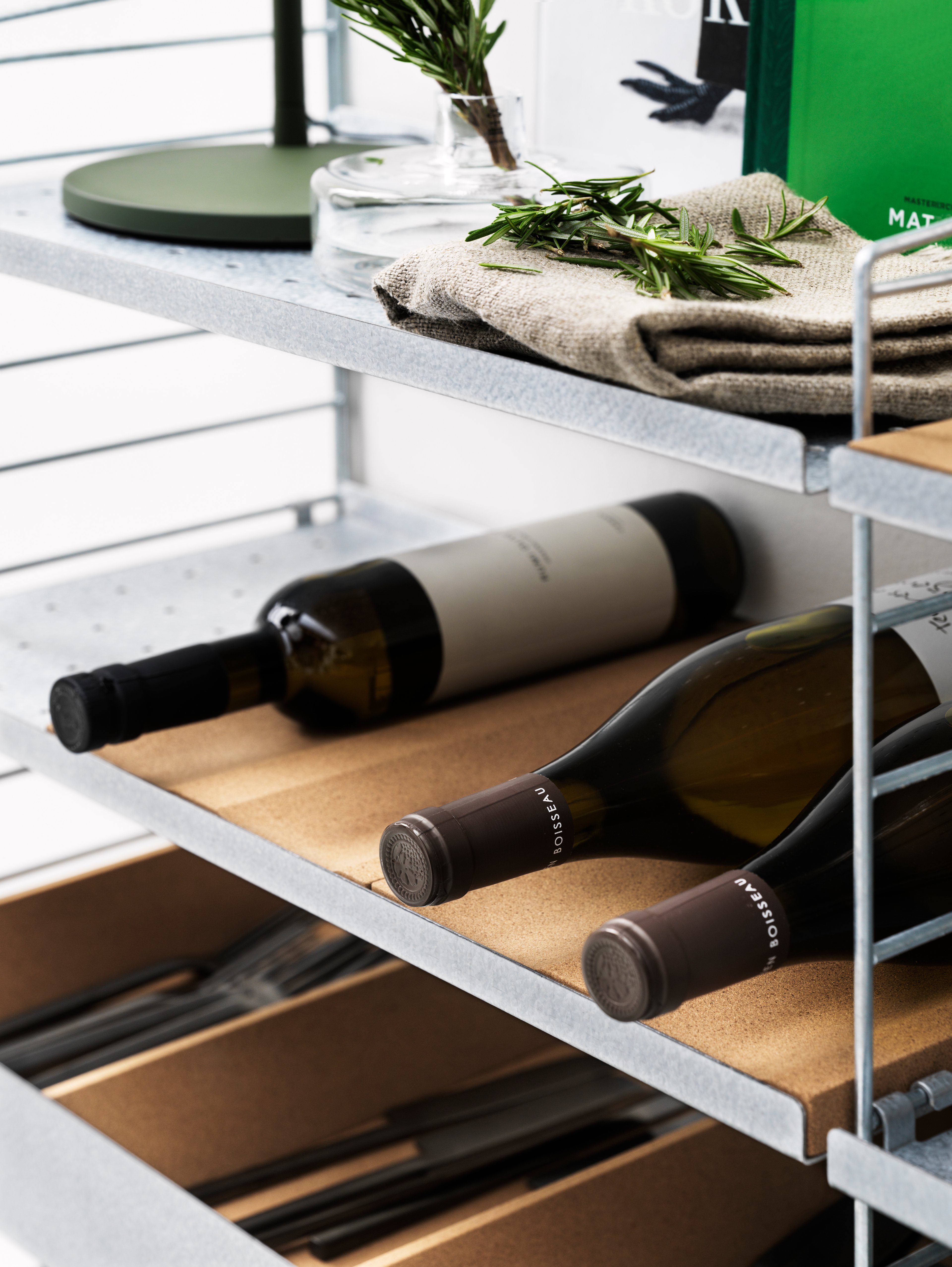 String shelf with white wall panels and metal shelves with low edge in white along with a cabinet with swing door in oak. Accessories such as rods, hanger racks, plate racks in white, organizers in beige, s-hooks in stainless steel along with a knife holder in massive oak.