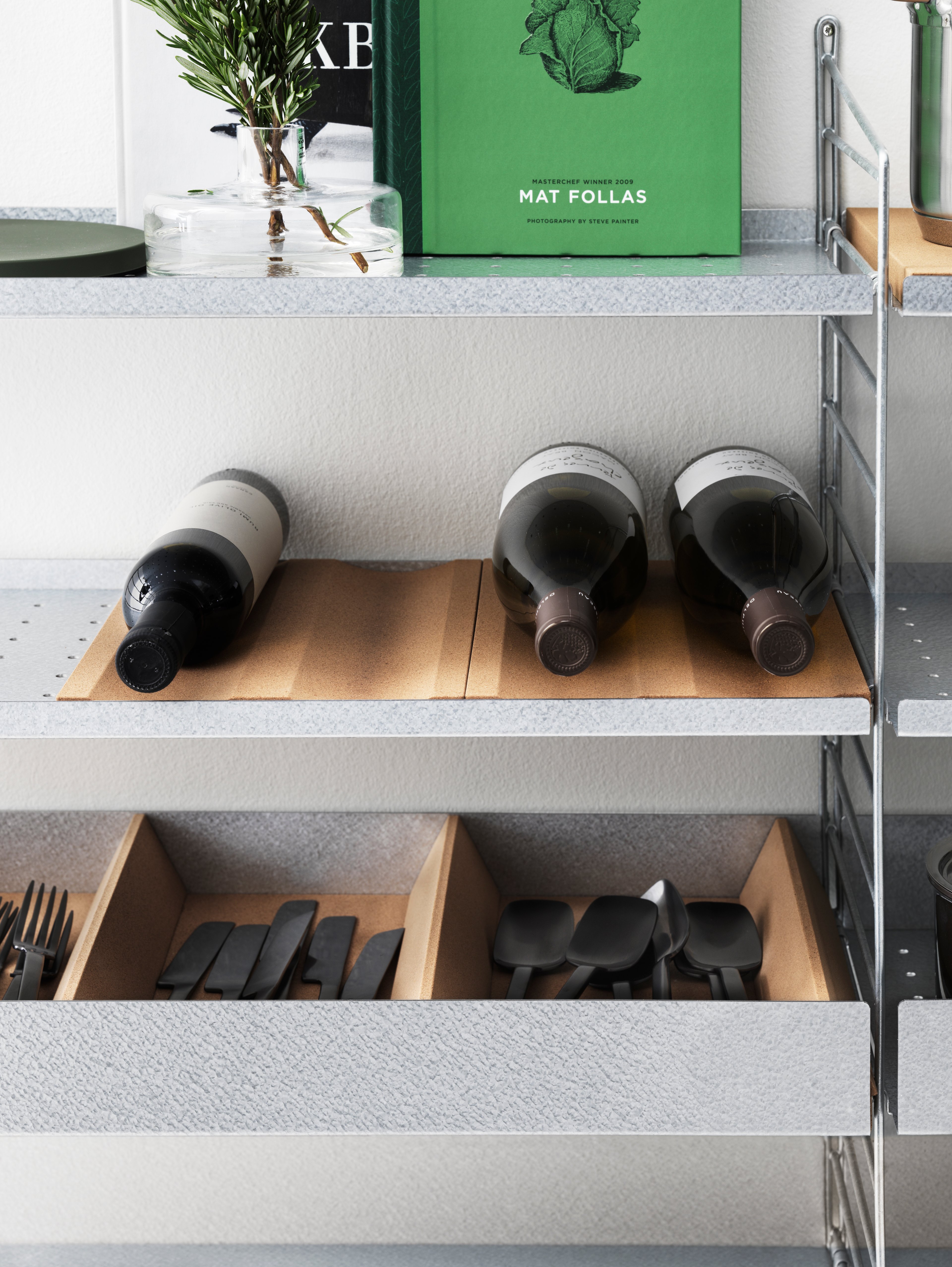 String shelf with floor panels from String System. Galvanized shelves and metal shelves with low edge in white along with bottle tray and dividers in cork. Perfect kitchen accessories.