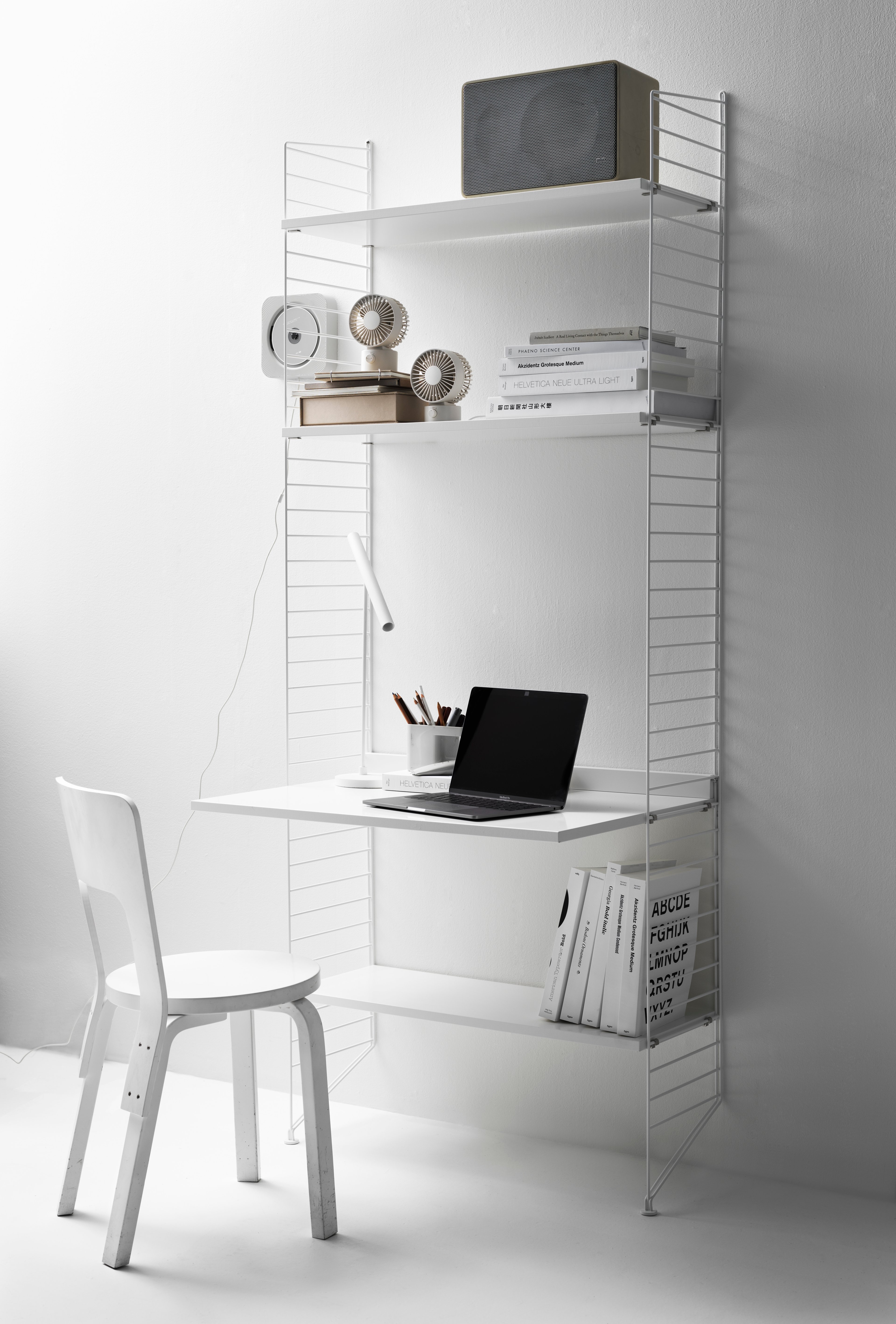 Combinaison d’étagères à poser au sol, gamme String System. Montants de sol, étagères, bureau et vide-poches muraux, blanc. Une configuration d’étagères optimale pour un bureau.