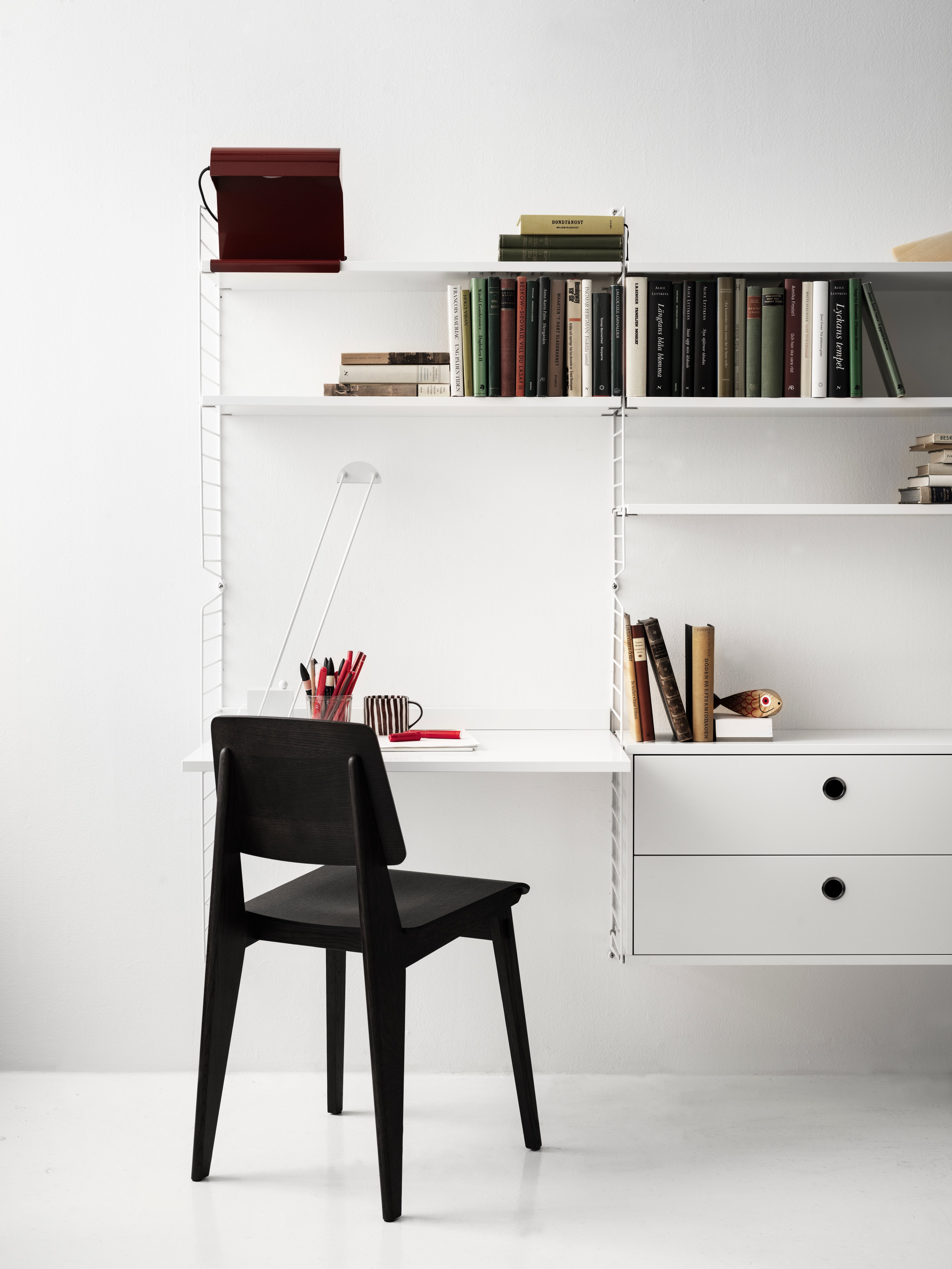 Wall-hung string shelf in white. Shelves, work desks and drawers create two separate work stations.