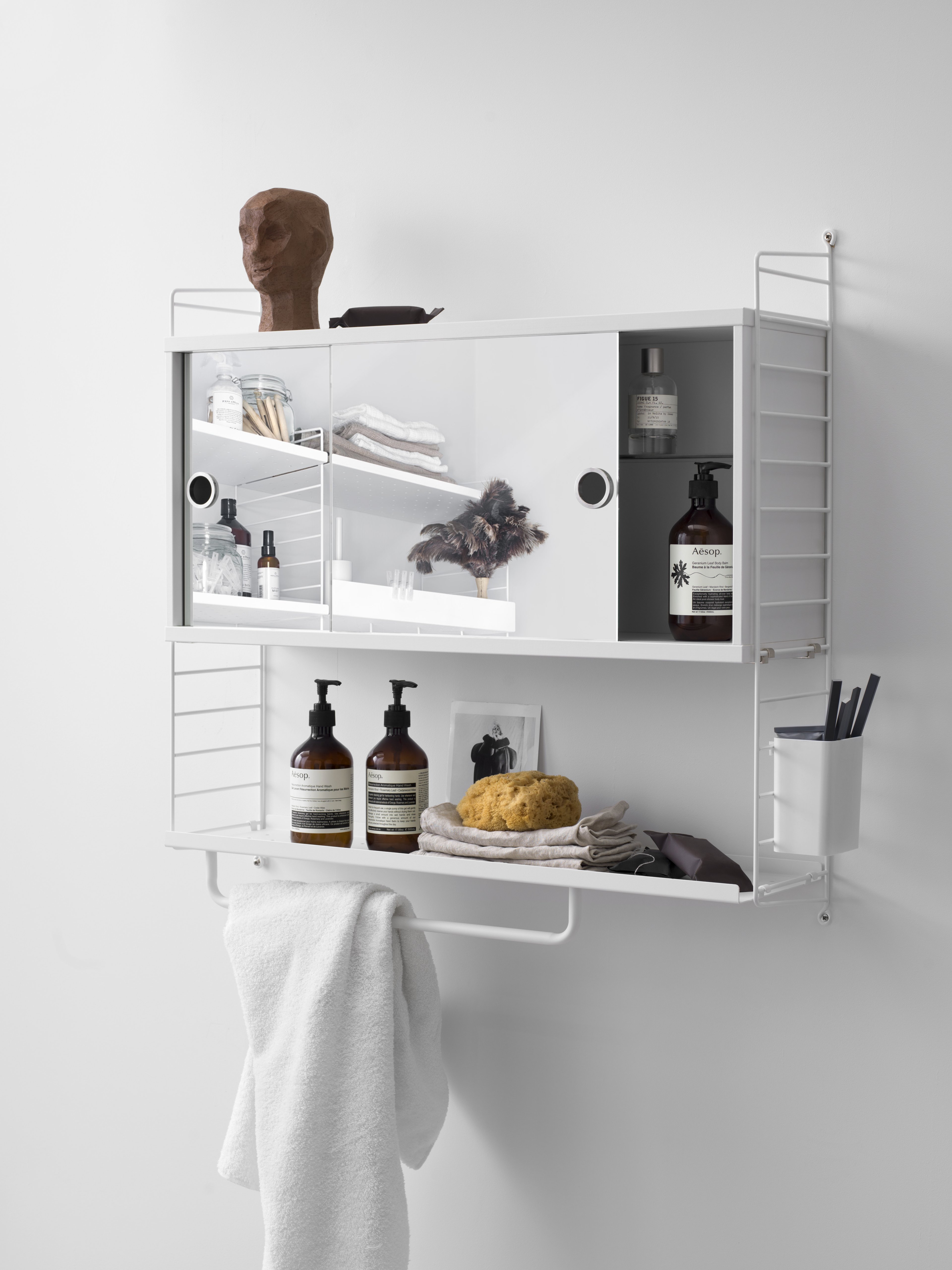 Wall mounted bathroom solution from String. Wall panels in white, cabinet with two mirror doors, metal shelf with low edge in white, rods in white and organizers in white.