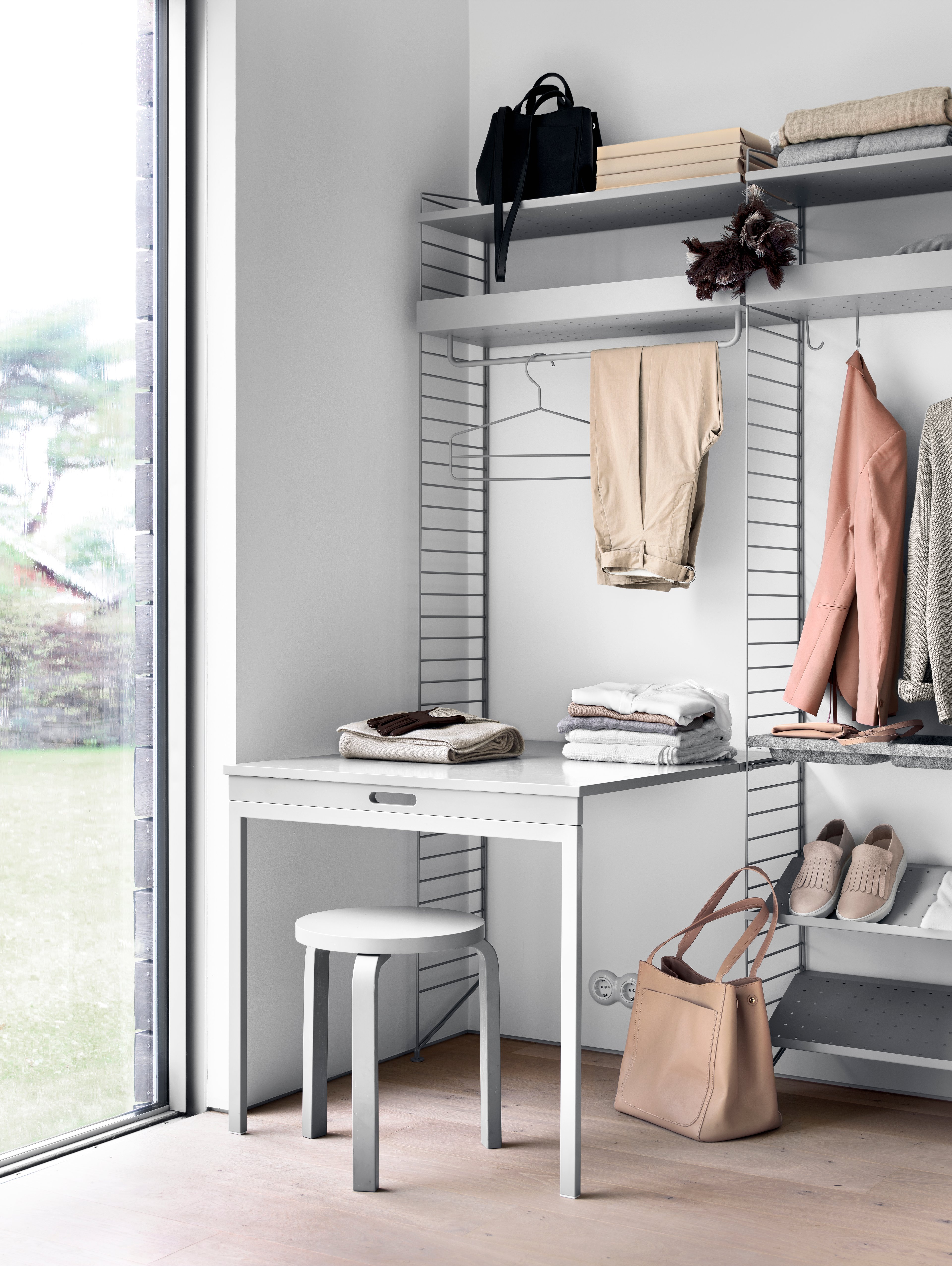 Floor mounted bedroom solution from String. Floor panels, metal shelves, shoe shelves and folding table in grey. rods, hooks and coat-hangers in grey.