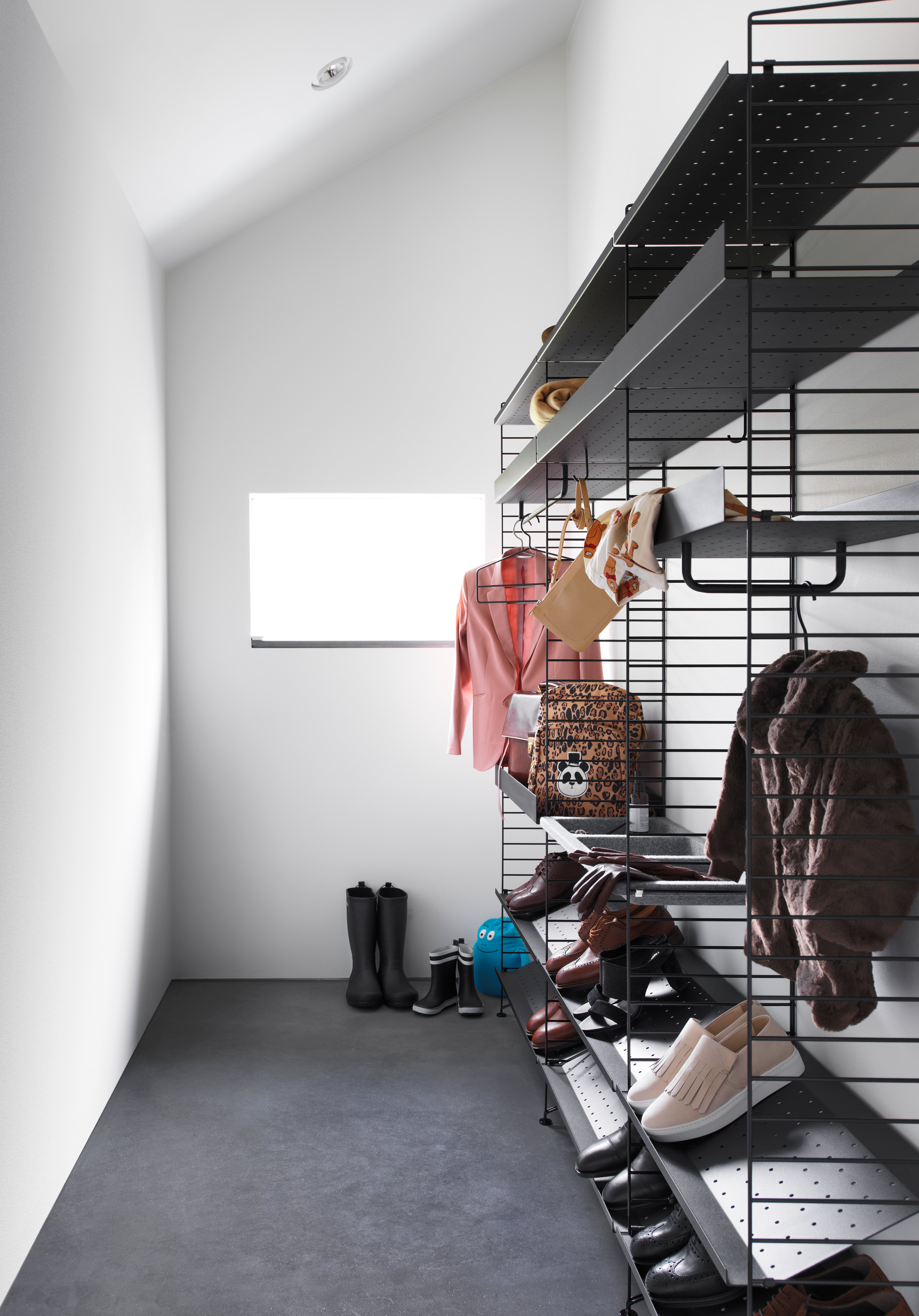 Floor mounted hallway solution from String. Floor panels, metal shelves and shoe shelves in black. rods, hooks and coat-hangers in black.