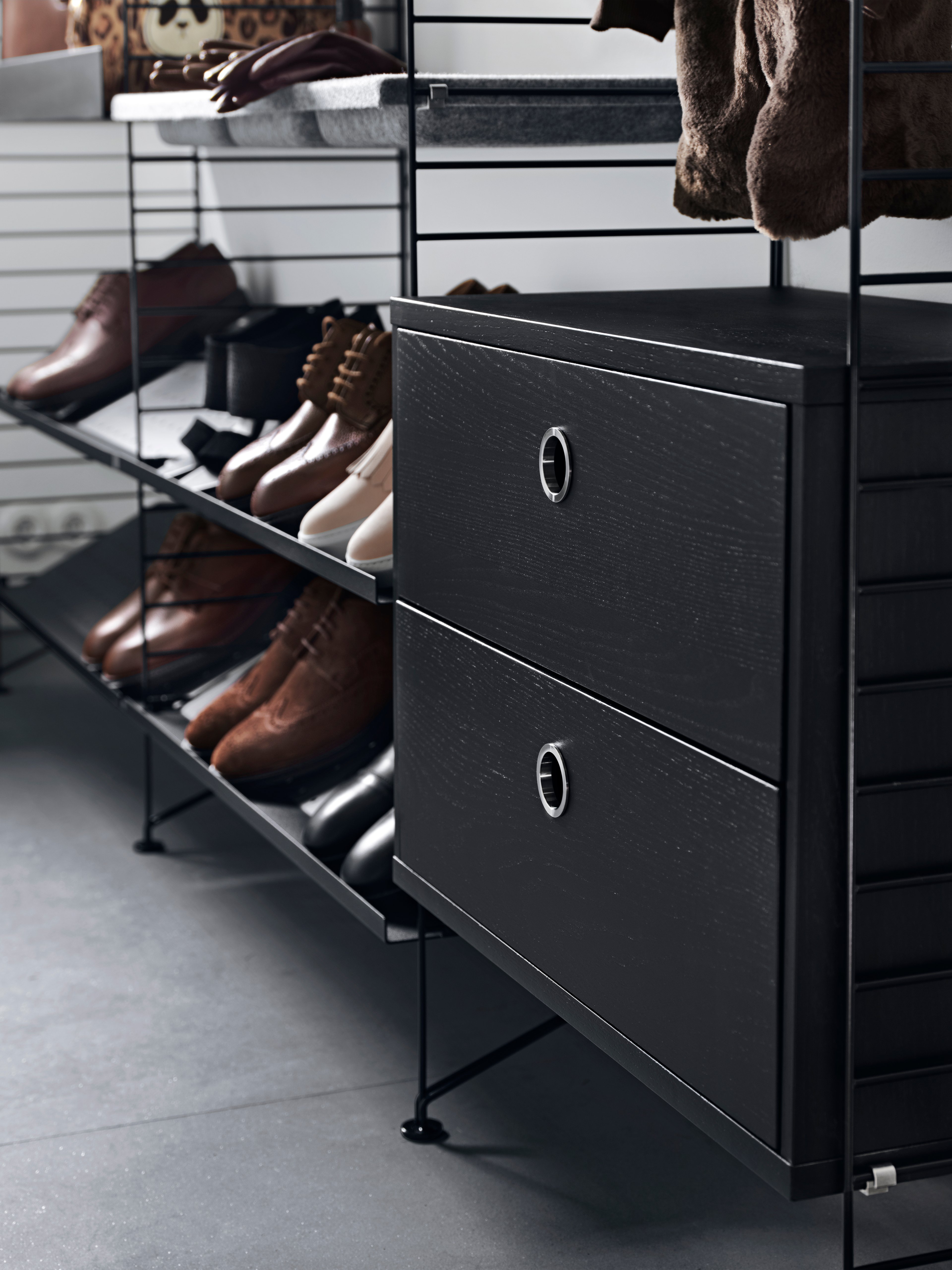 Solución de pasillo montada en suelo de String. Paneles de suelo y estantes metálicos para zapatos en negro. Cajoneras en fresno teñido negro Estantes Bowl de fieltro en gris claro.