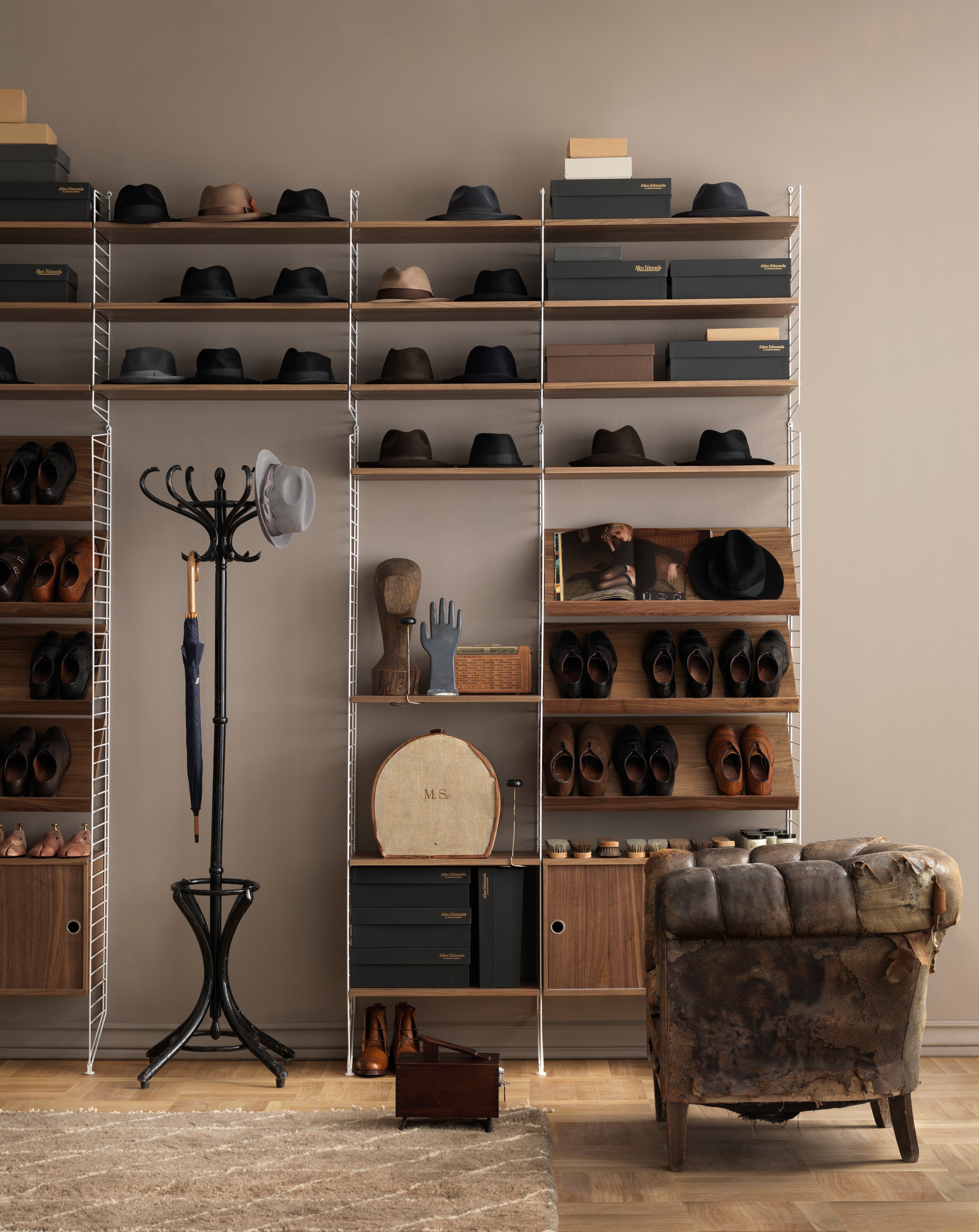 Floor mounted hallway  solution from String. Floor panels and wall panels in white. shelves, magazine shelves, cabinet with sliding doors and display cabinet in walnut.