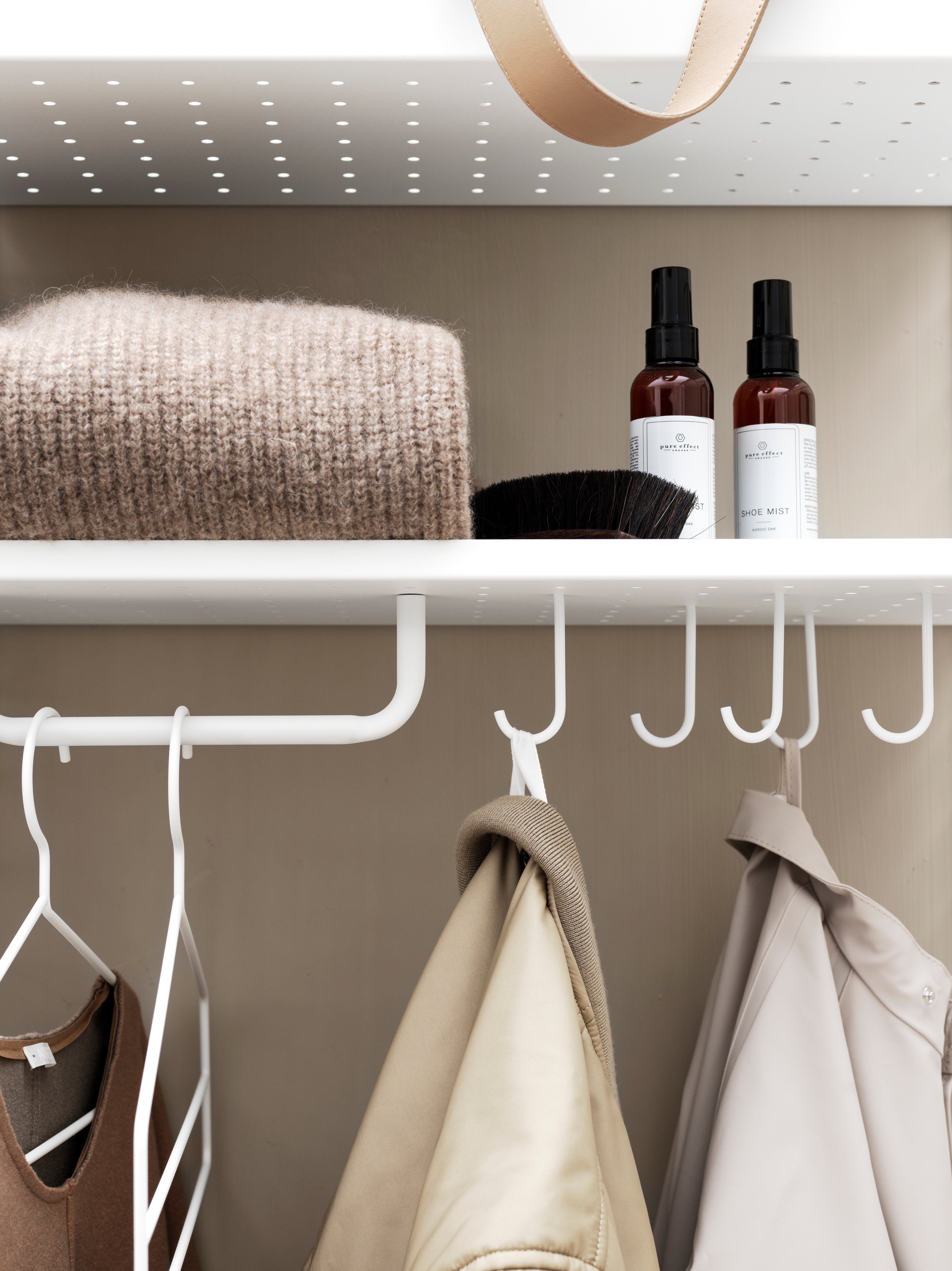 Wall mounted hallway solution from String. Wall panels, metal shelves low, hooks, coat hangers and rod in white.