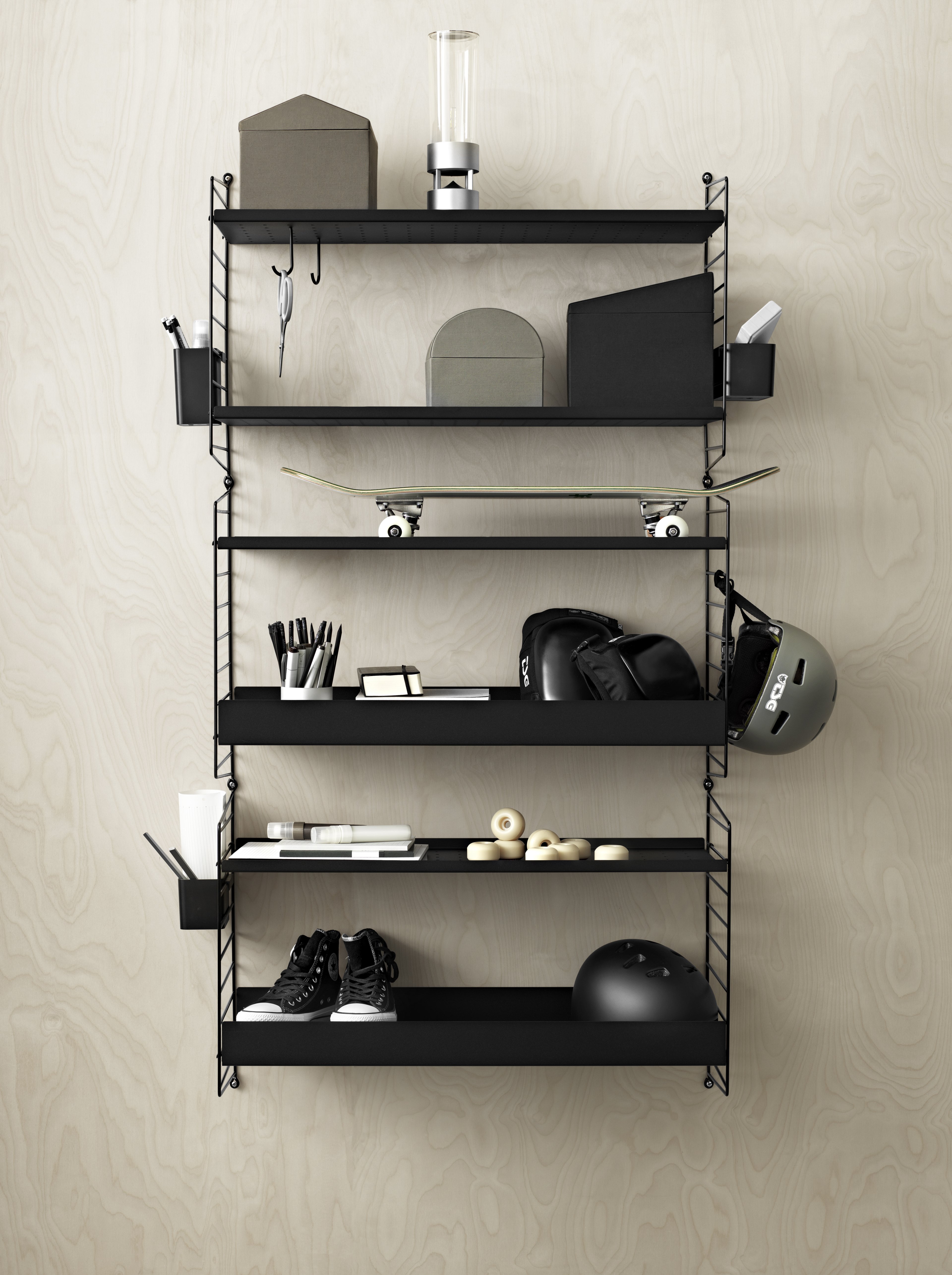 Wall mounted kids room solution from String. Wall panels in black. Metal shelves high and metal shelves low in black. Organizers and hooks in black.