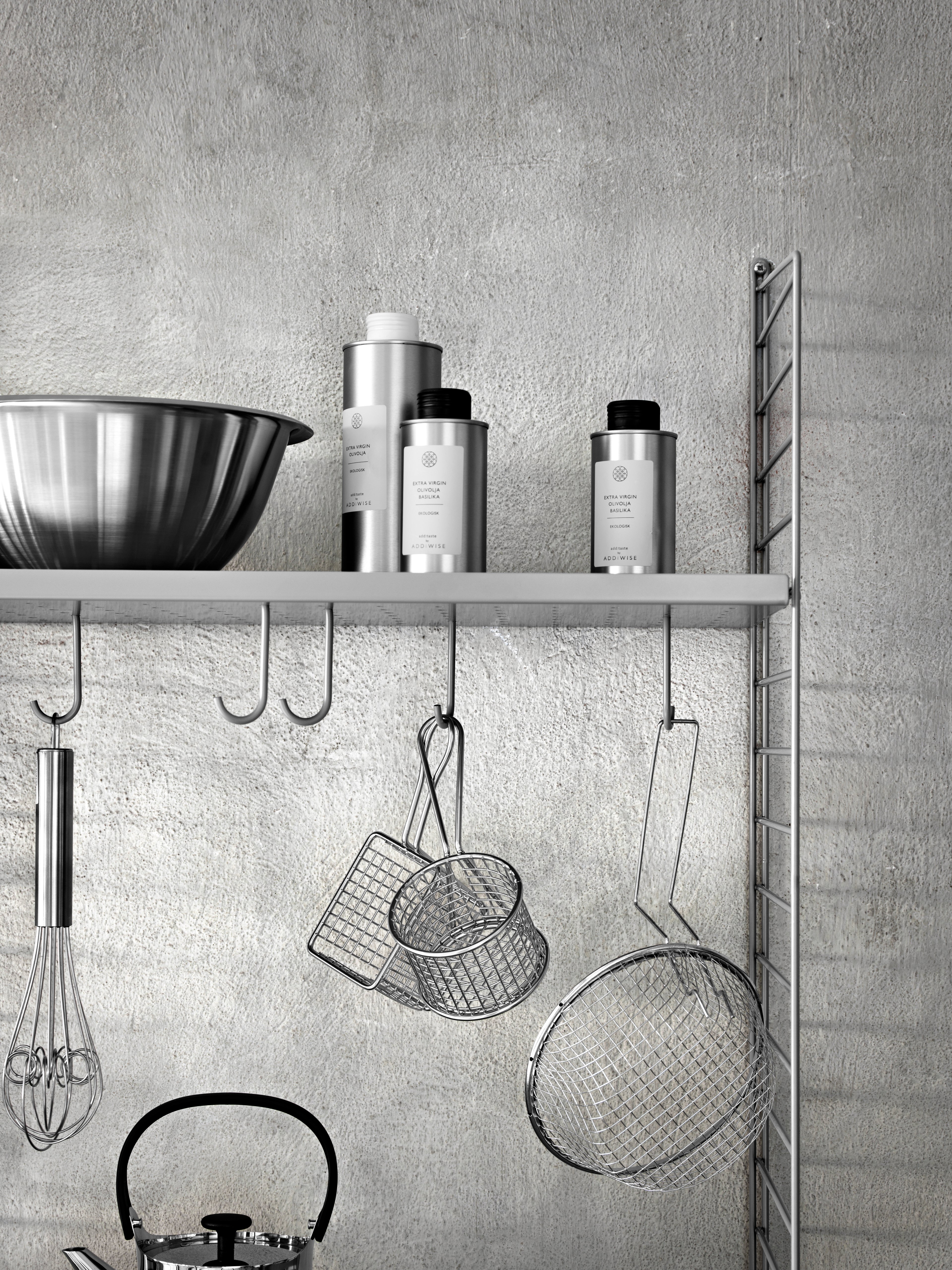 Wall mounted kitchen solution from String. Wall panels and metal shelves low in grey. Rods and hooks in grey.