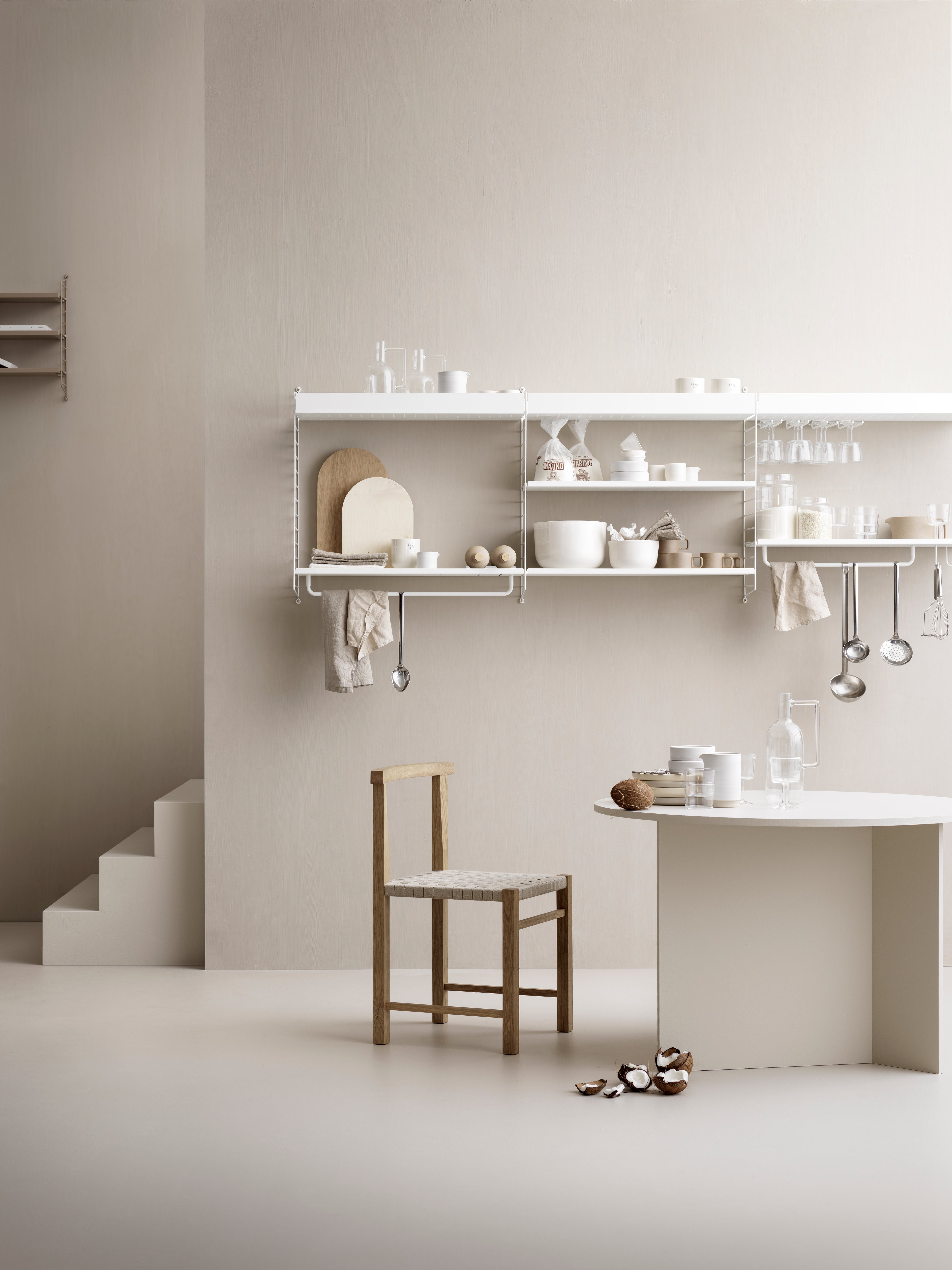 String shelving system for your kitchen. Wall panels in white, metal shelves with high and low edge in white, j hooks in white, hanger-racks in white and rods in white. String Pocket shelf with perforated metal shelves in the colour taupe.