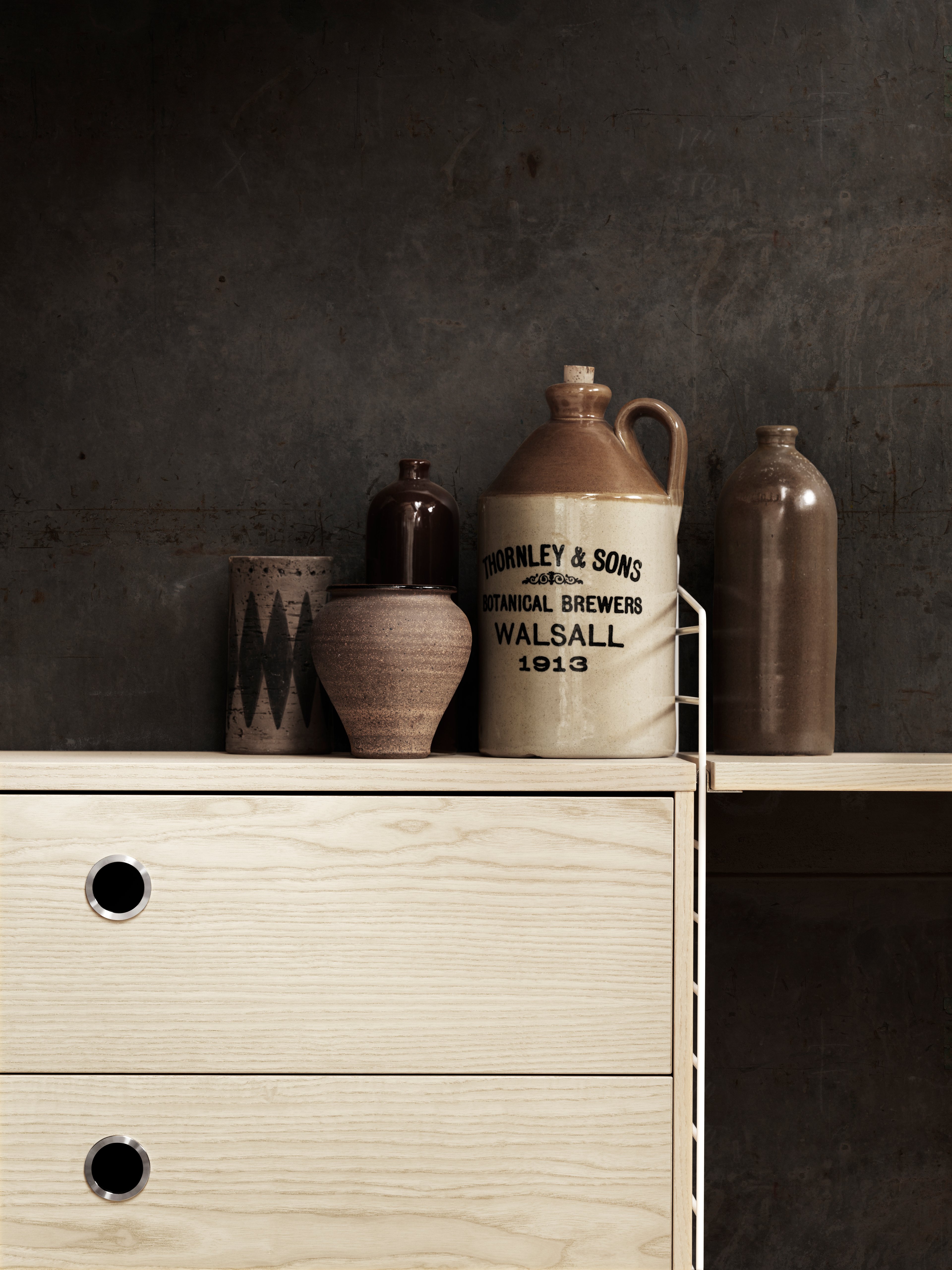 Wall mounted living room solution from String. Wall panels in white. Shelves and chest of drawers in ash.