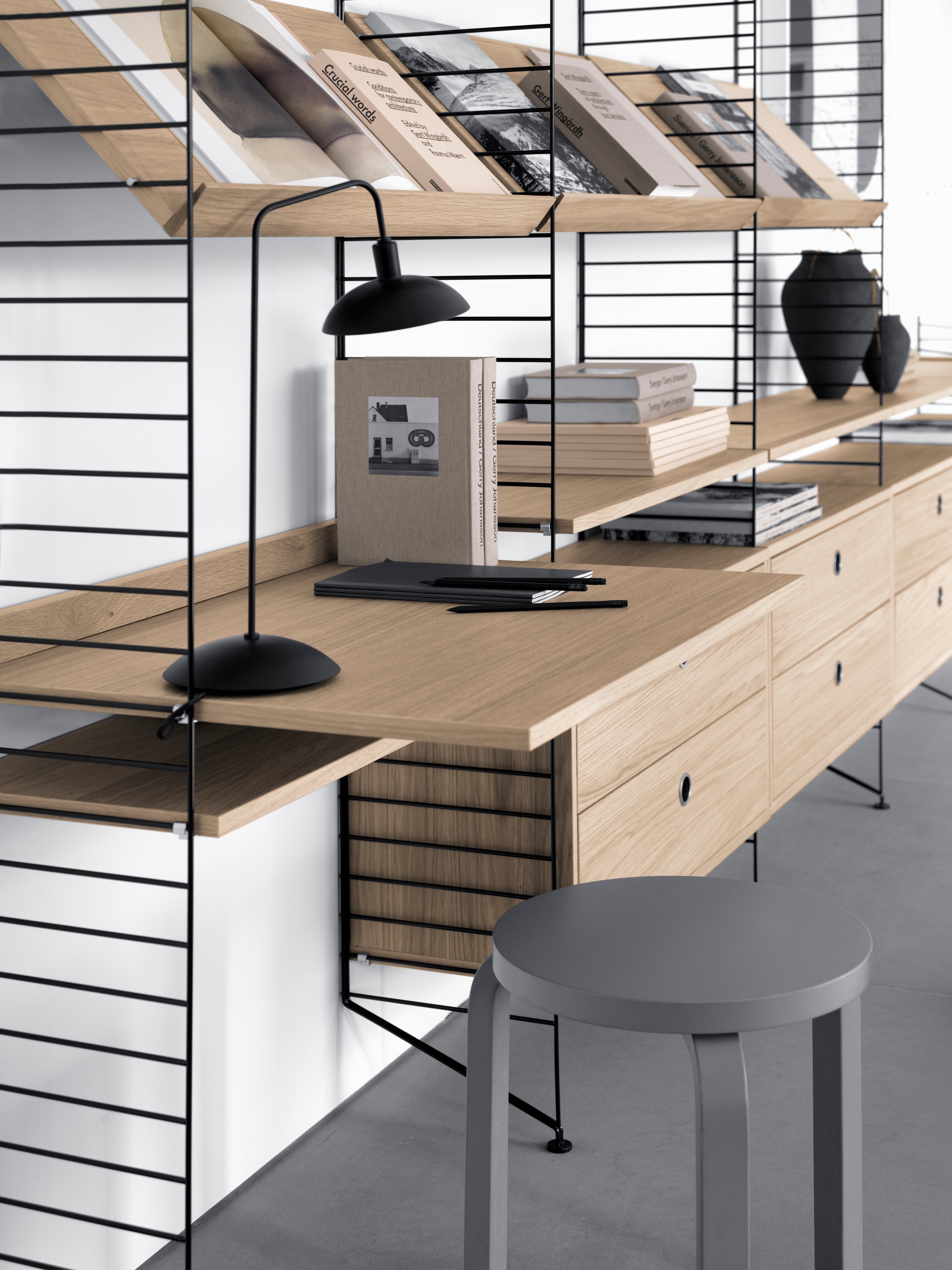 Floor mounted livingroom solution from String. Floor panels in black. Shelves, work desks and magazine shelves solid in oak. Chest of drawers in oak.