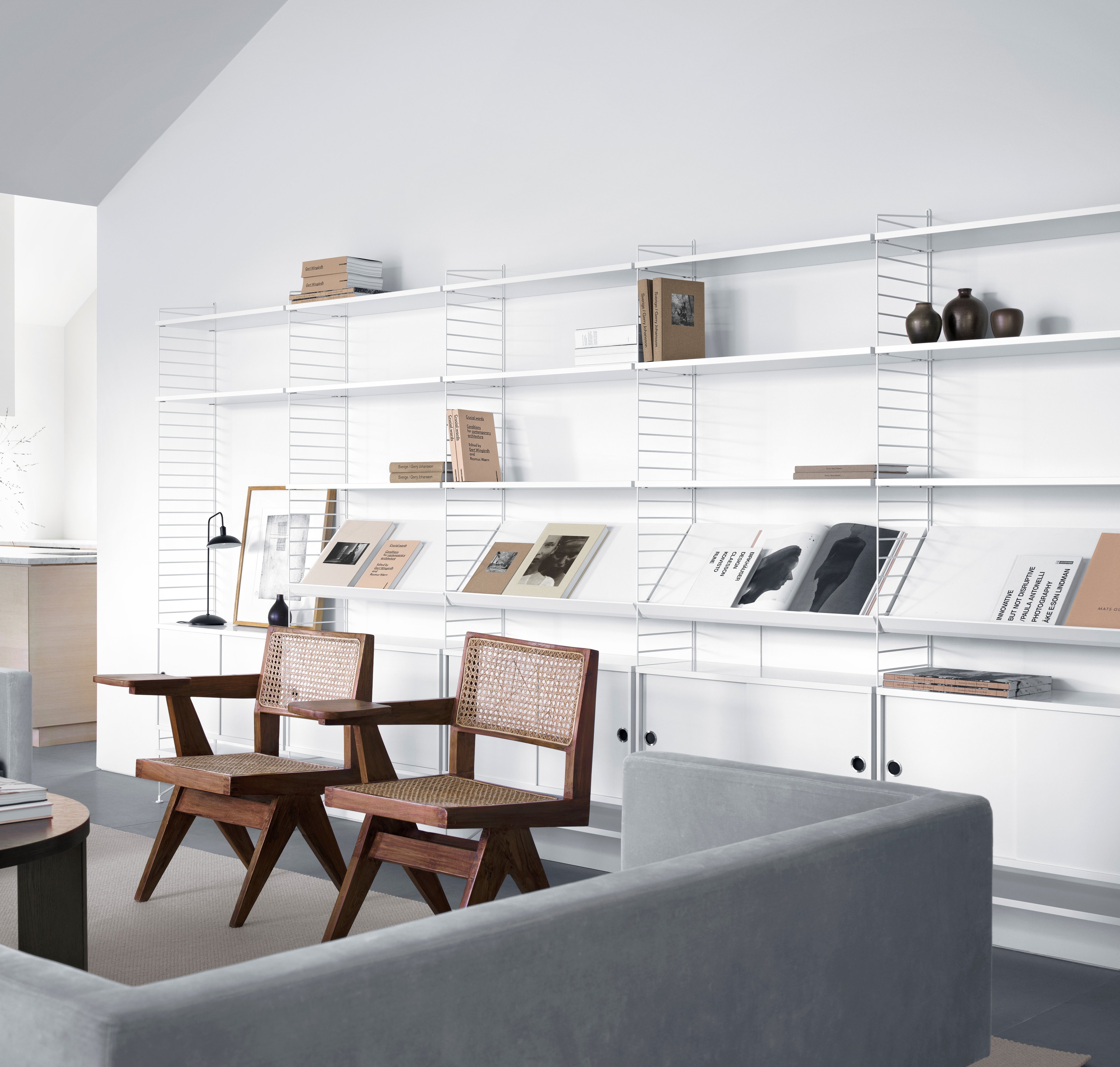 Floor mounted living room solution from String. Floor panels and shelves in white. Magazine shelves solid and cabinet with sliding doors in white.