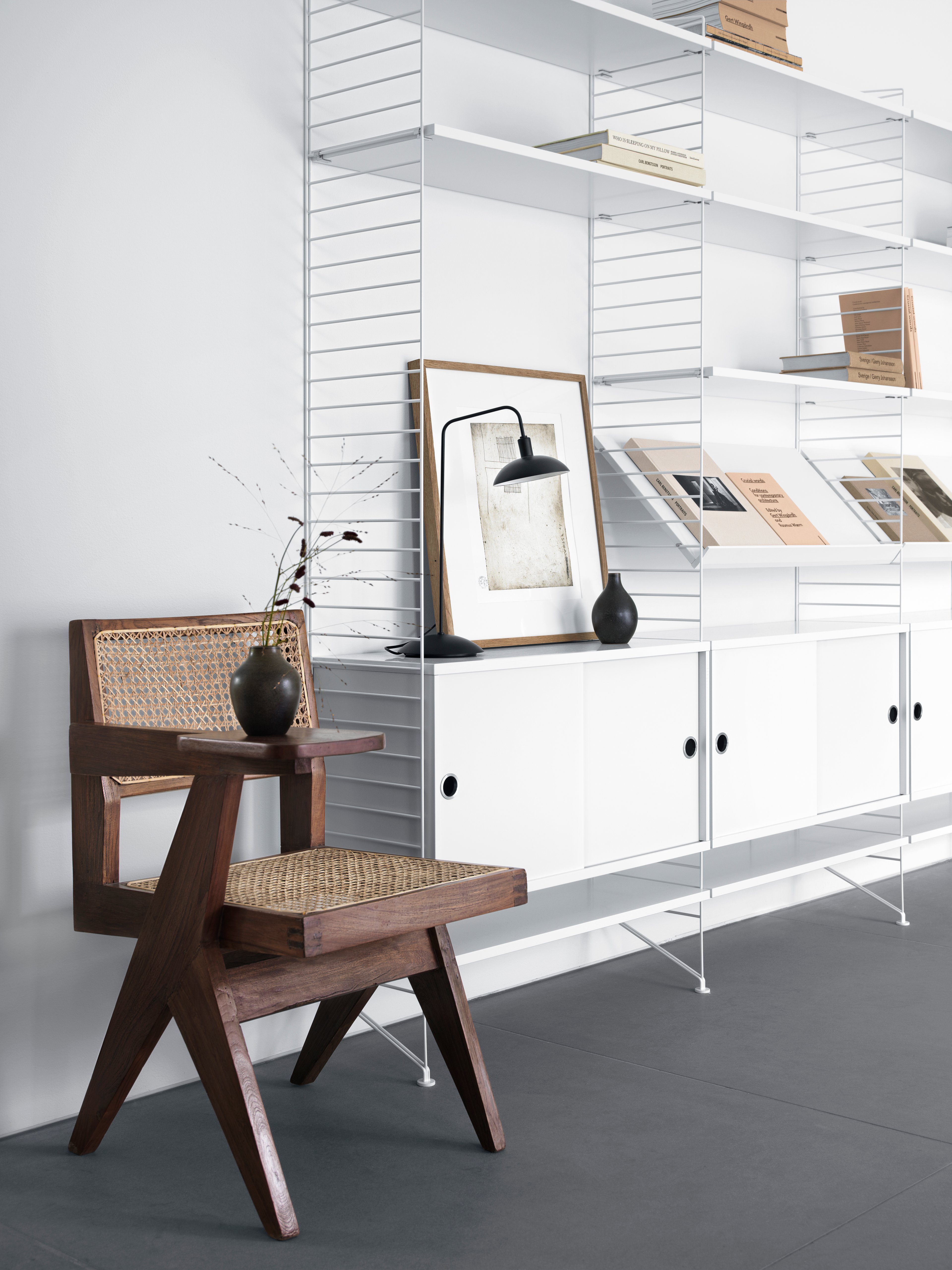 Floor mounted living room solution from String. Floor panels and shelves in white. Cabinet with sliding doors in white. Magazine shelves solid in white.