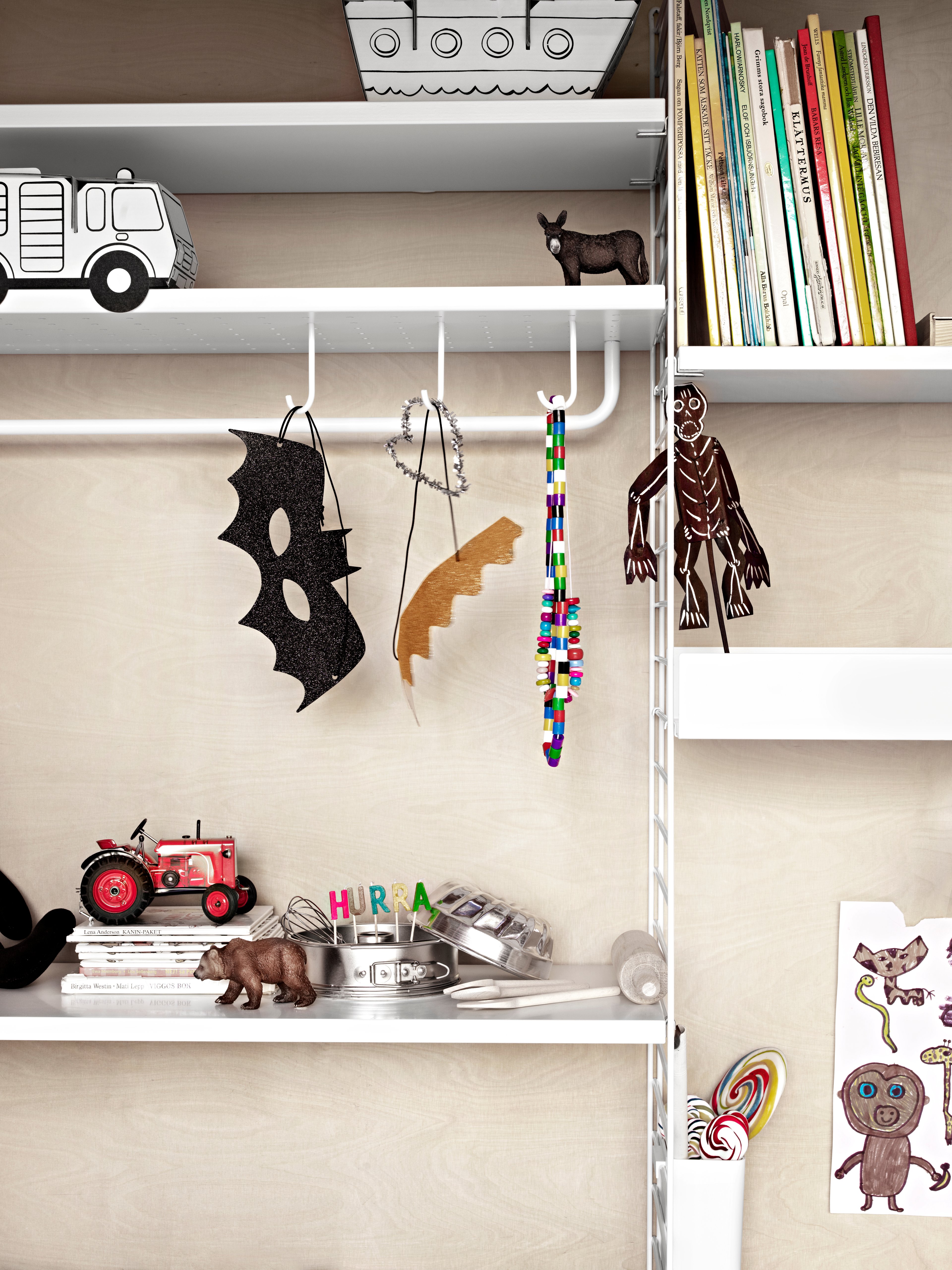 Wall mounted kids room solution from String. Wall panels and shelves in white. Metal shelves high and metal shelves low in white. Rods and hooks in white.