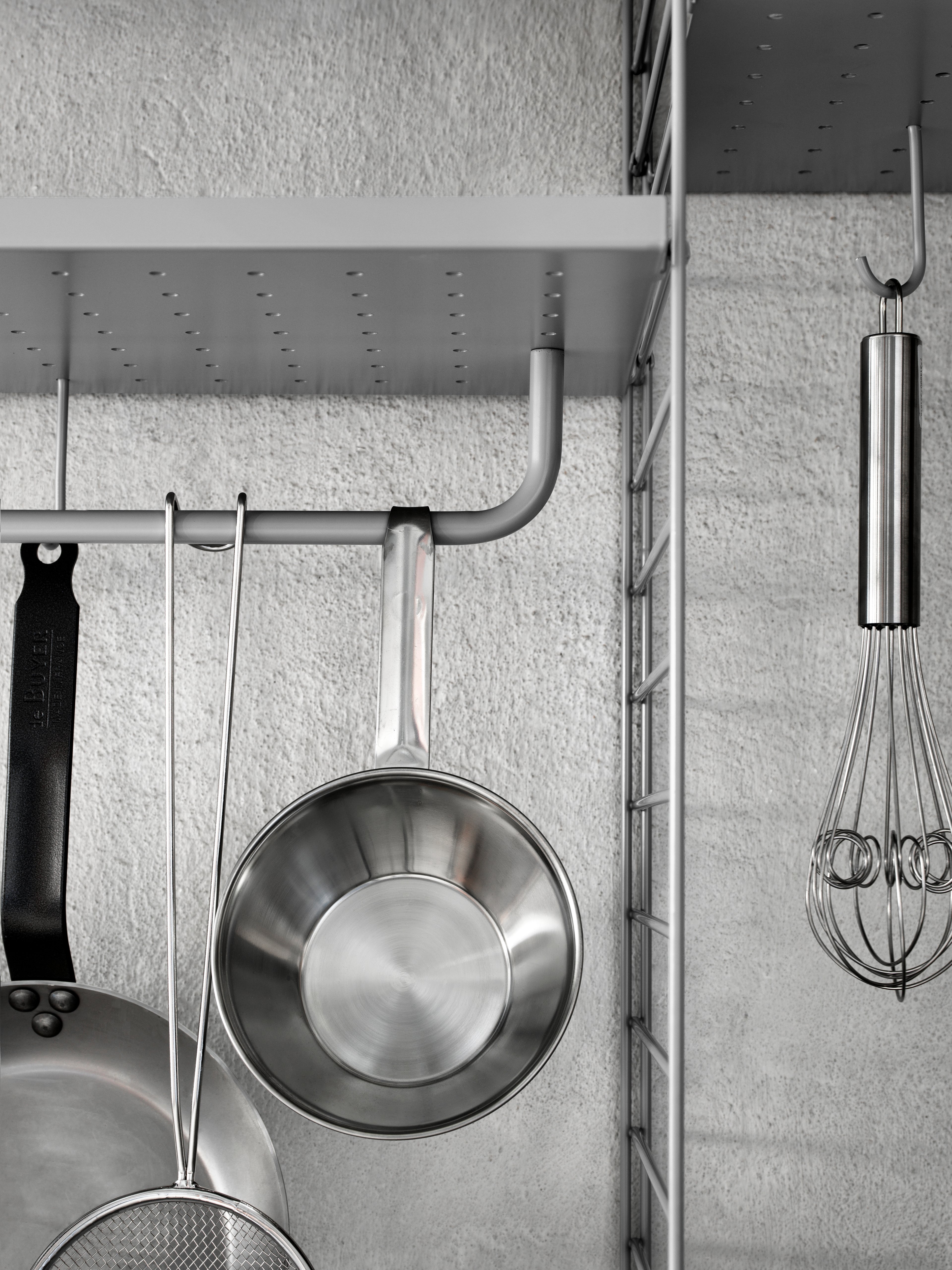 Wall mounted kitchen solution from String. Wall panels and metal shelves low in grey. Rods and hooks in grey.