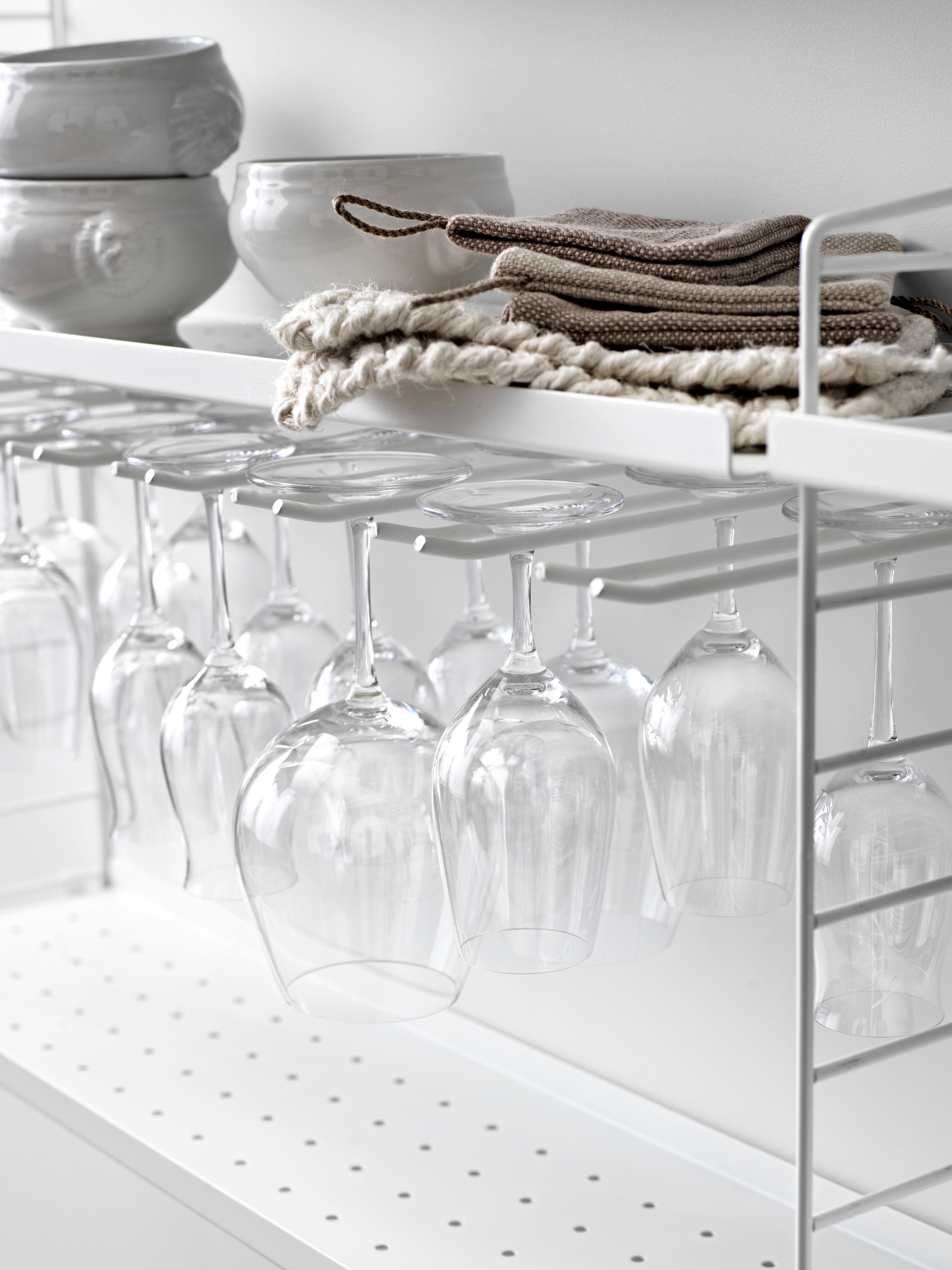 Wall mounted kitchen solution from String. Wall panels and metal shelves low in white. White hanger racks.