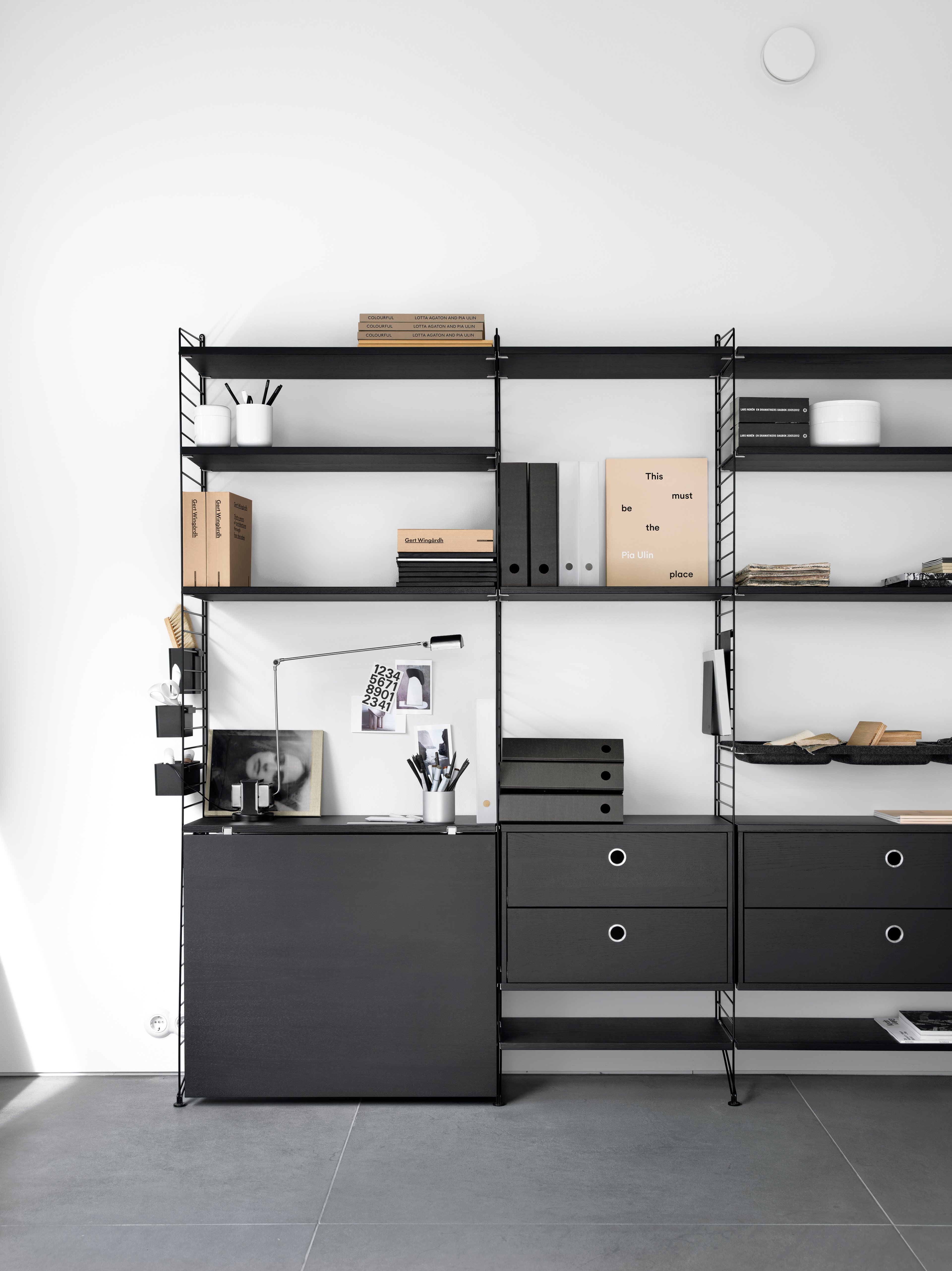 Floor mounted workspace solution from String. Floor panels in black. Shelves in black stained ash. Folding tables and chest of drawers in black stained ash. Bowl shelves felt in anthracite. Organizers and magazine holders in black.